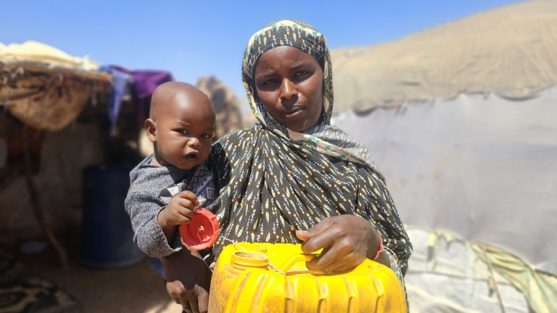 Portrait of woman holding both a boy and a water can